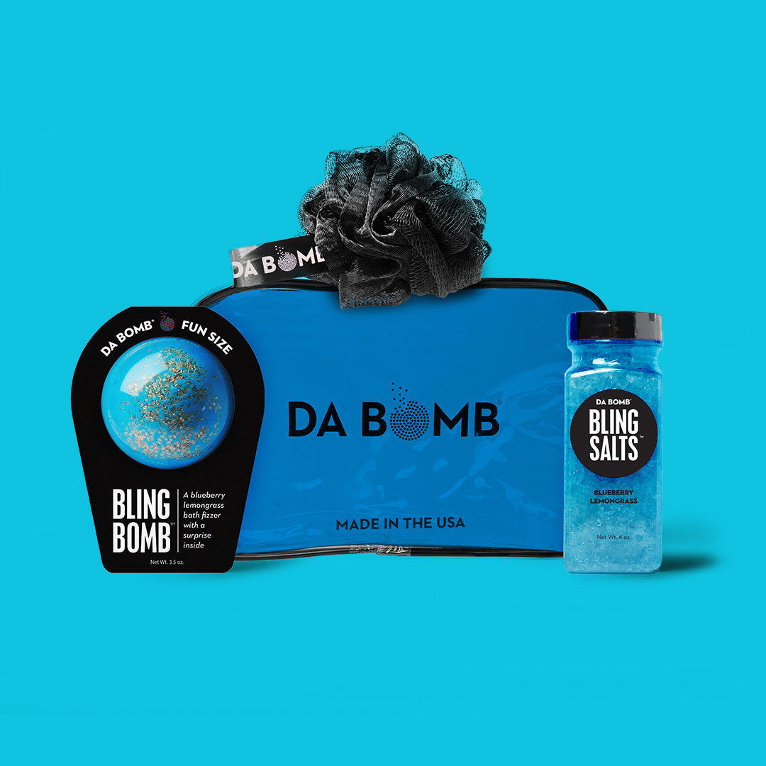 a blue gift set comprised of bath bomb, bath salts and loofah on blue background