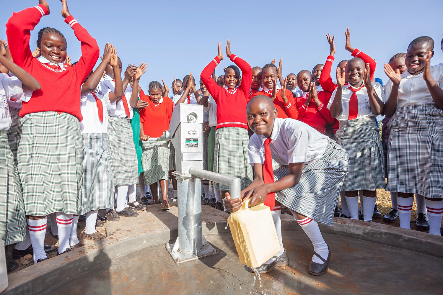 African people around water well clapping