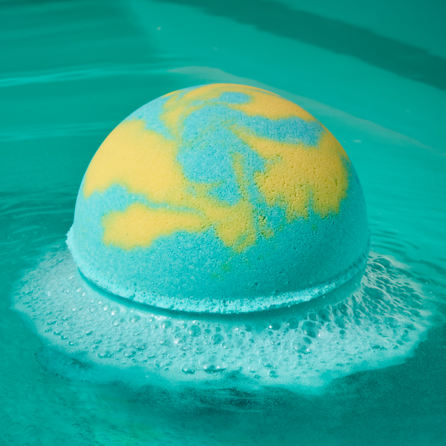 Green and yellow swirl bath bomb fizzing in water