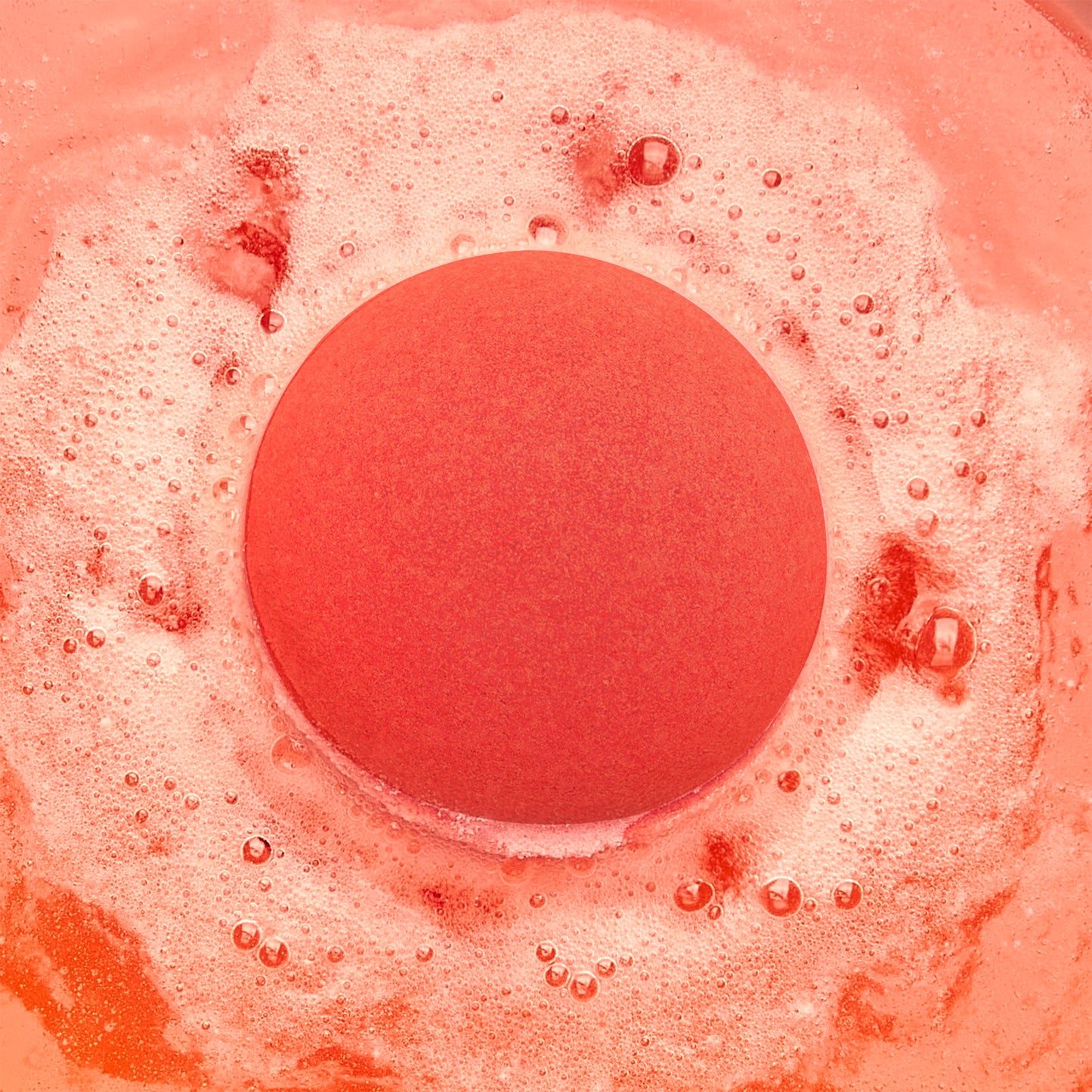 a red fizzing bath bomb in red water