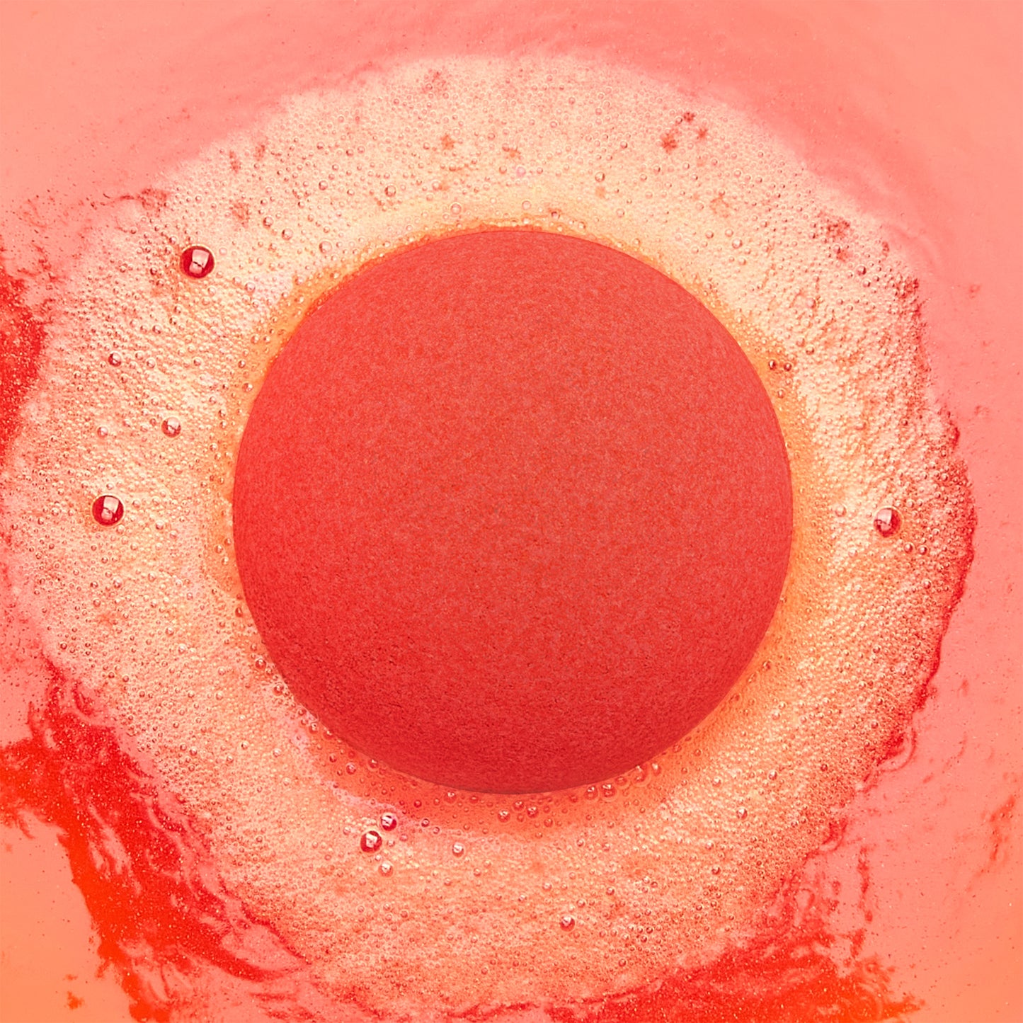 a red fizzing bath bomb in red bubbly water