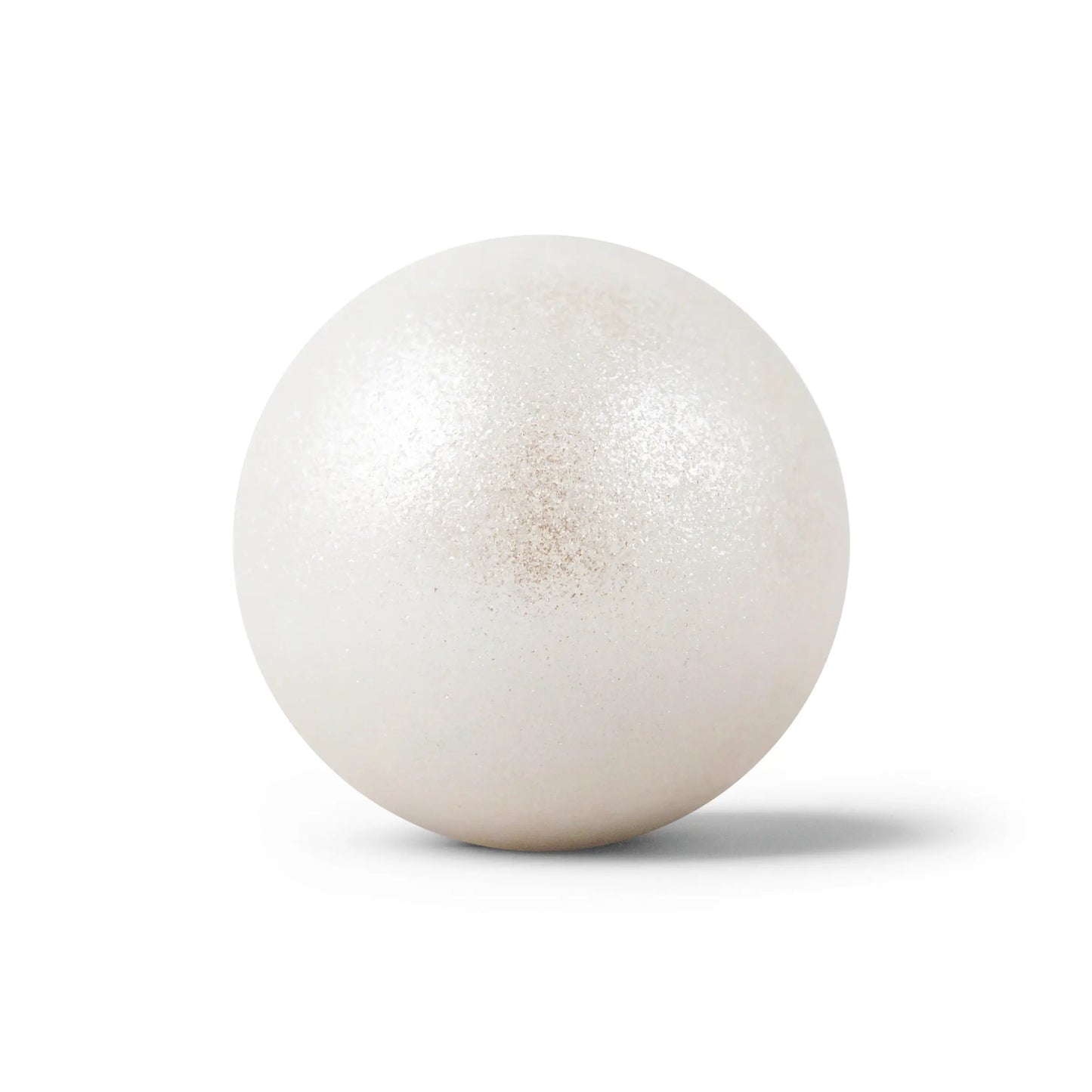 Sparkly white round bath bomb out of packaging on white background.