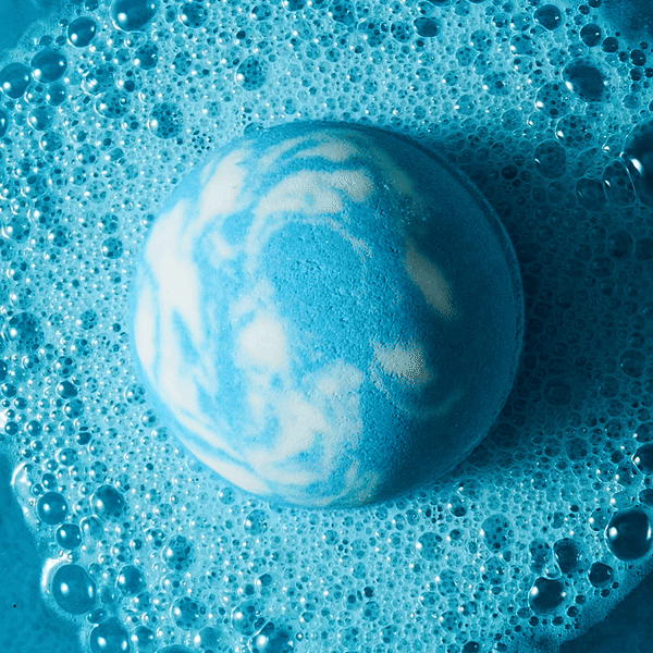 GIF of fizzing blue and white bath bomb in blue water