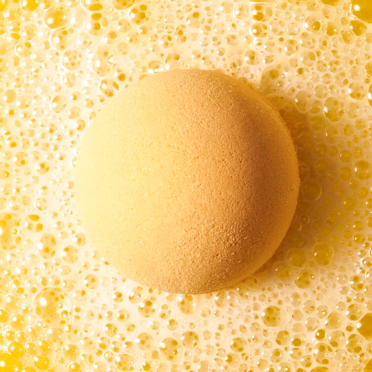 an animated GIF of orange bath bomb fizzing in water