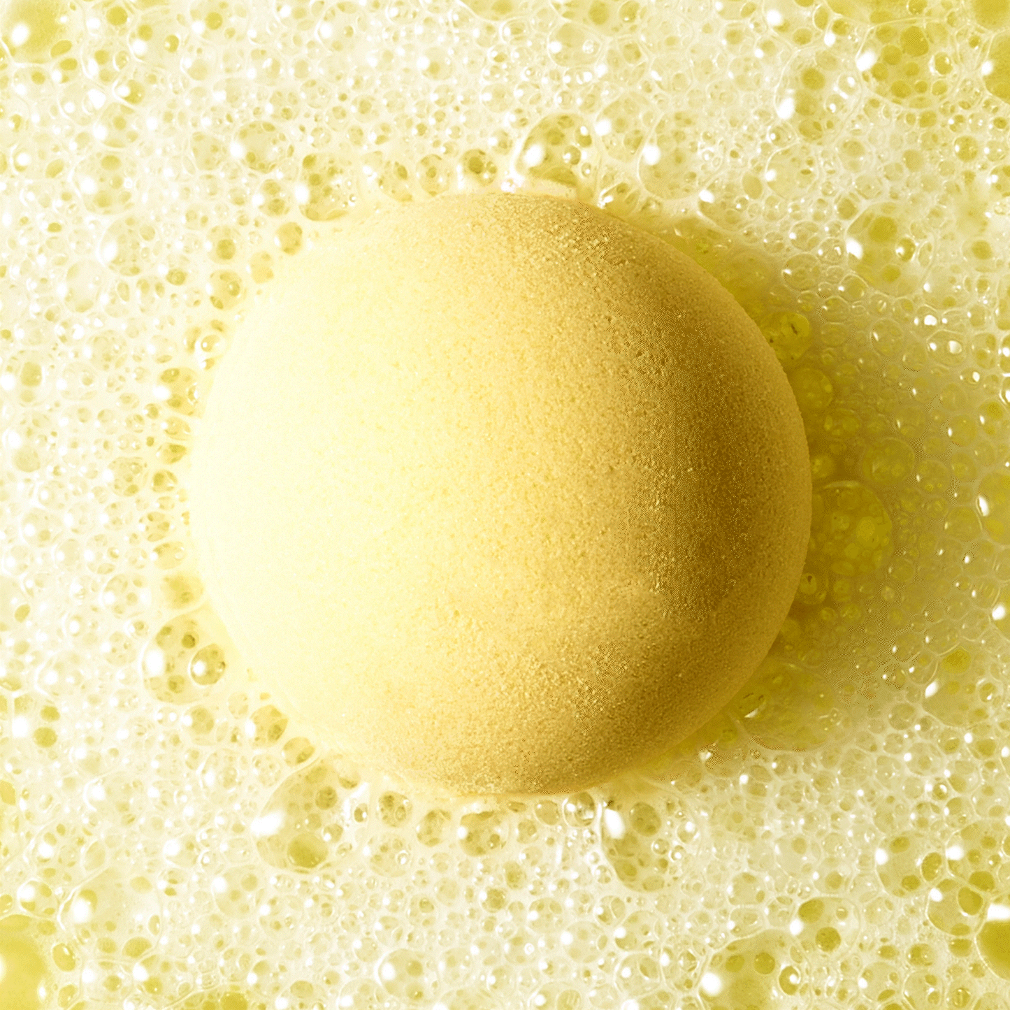 an animated GIF of yellow bath bomb fizzing in water