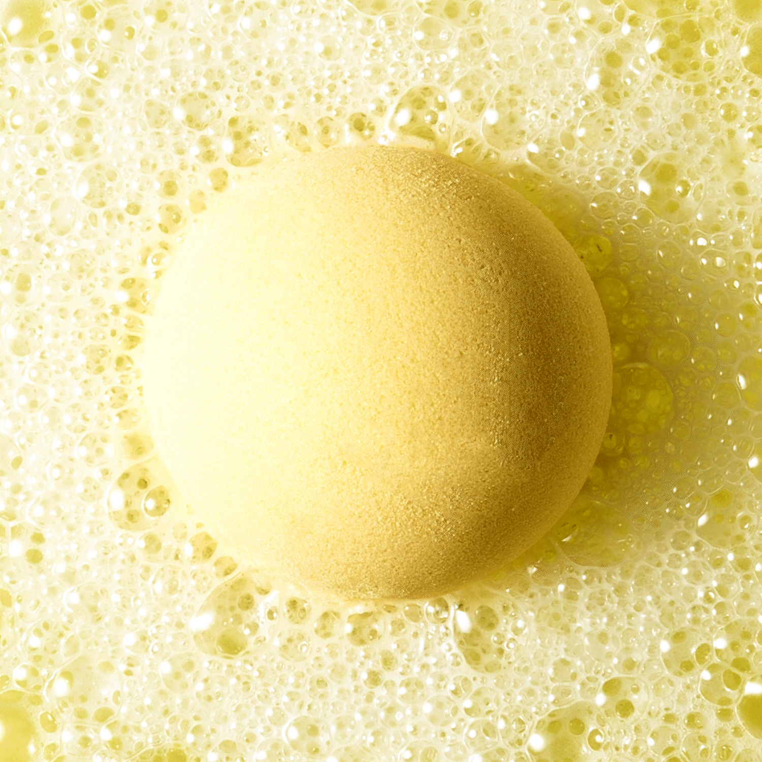 an animated GIF of yellow bath bomb fizzing in water