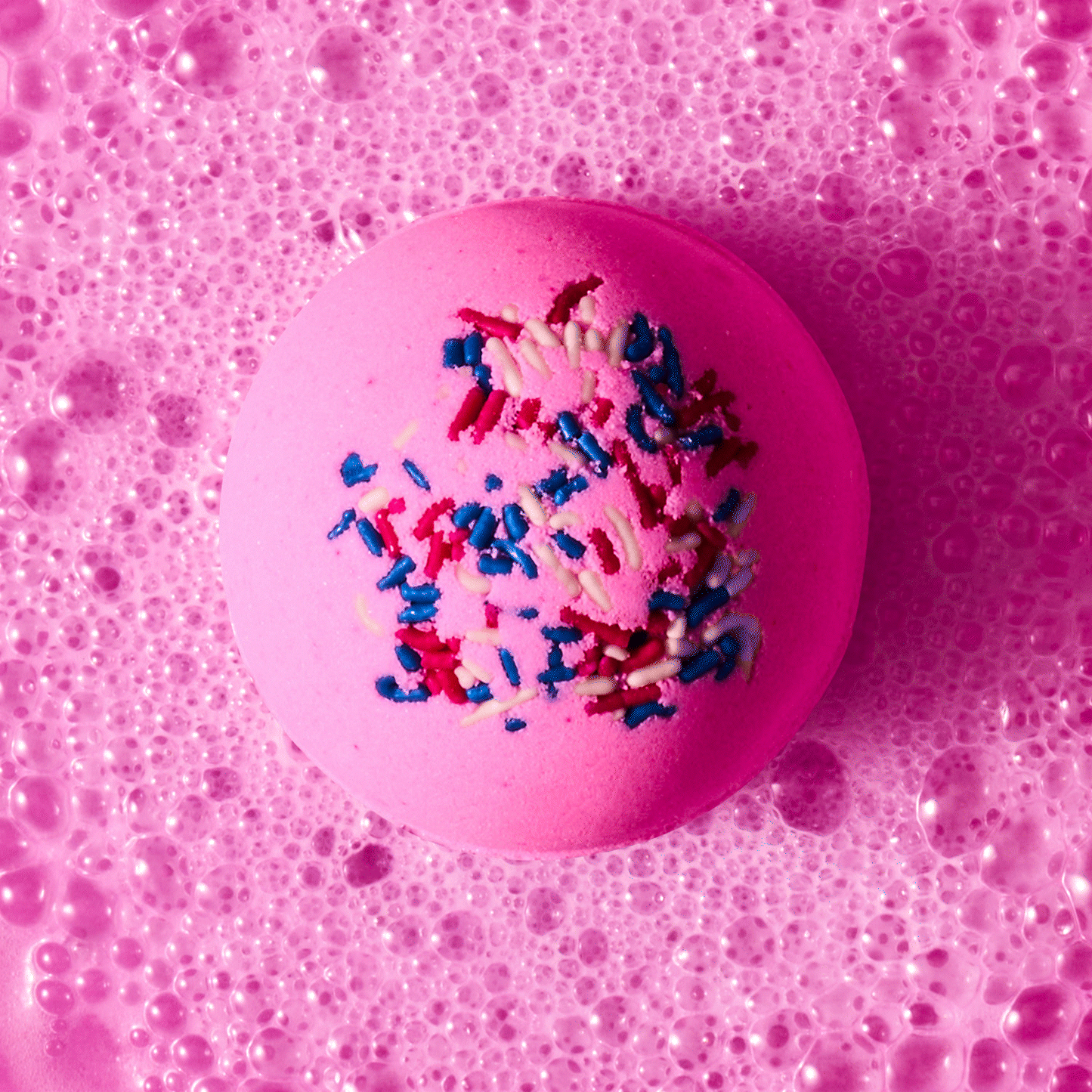 pink candy bath bomb with sprinkles fizzing in water