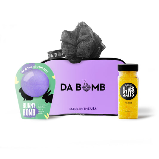 a purple gift set comprised of easter bath bomb, yellow bath salts and black loofah