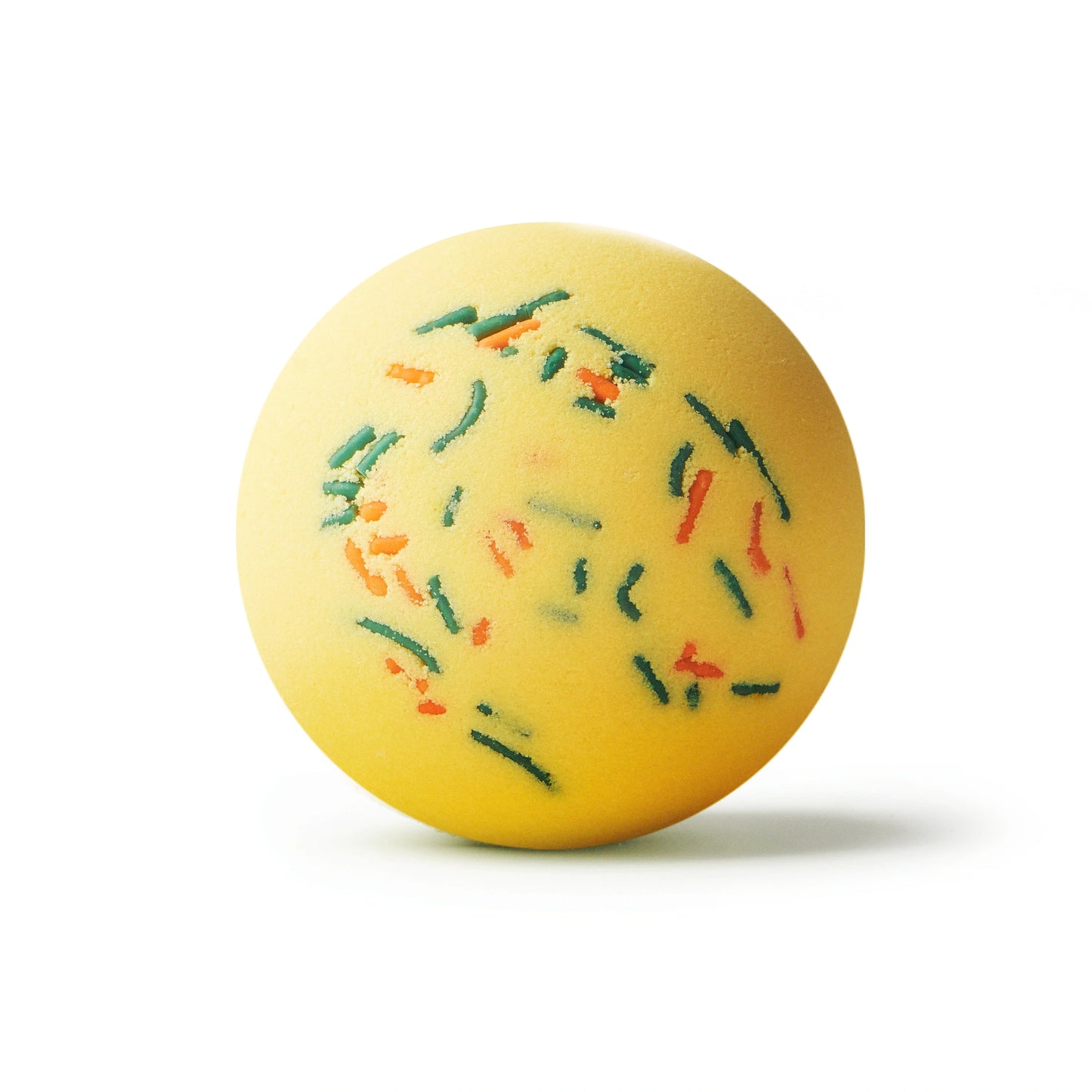 Yellow bath bomb with green and orange sprinkles on a white background