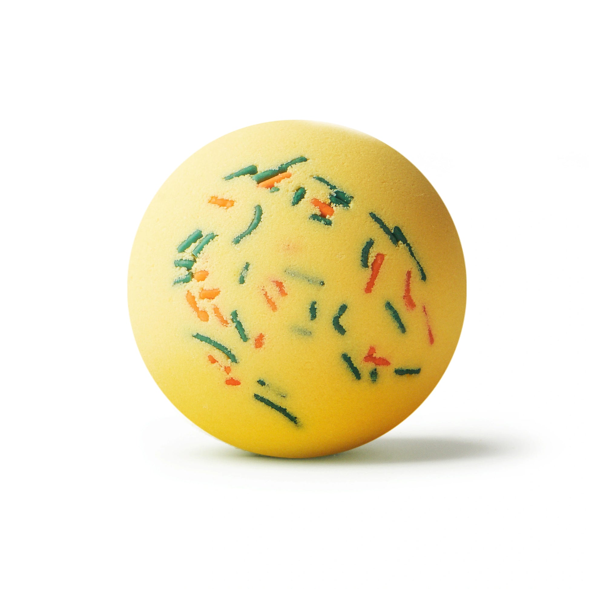 Yellow bath bomb with green and orange sprinkles on a white background