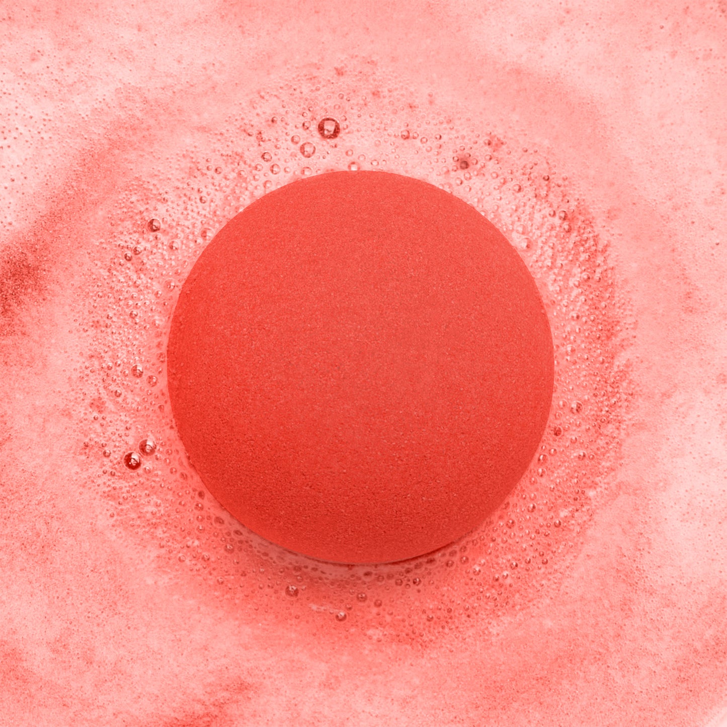 a red fizzing bath bomb in red bubbly water