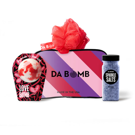 a purple, pink and red striped gift set comprised of black bath bomb with red and pink hearts, purple bath salts and red loofah