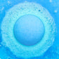a blue fizzing bath bomb in blue water