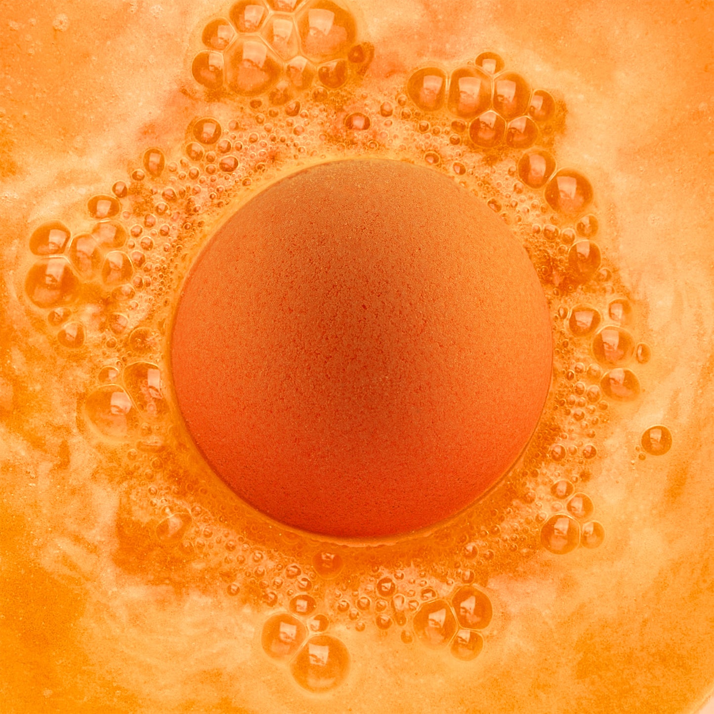 an orange fizzing bath bomb in orange water