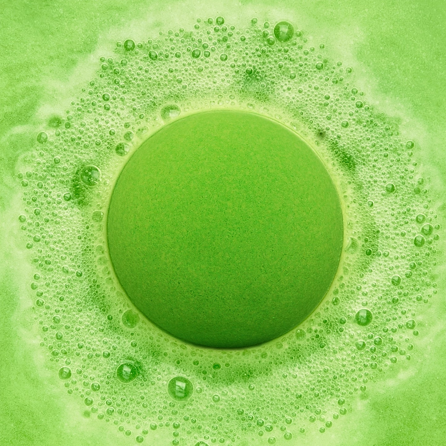 a green fizzing bath bomb in green water