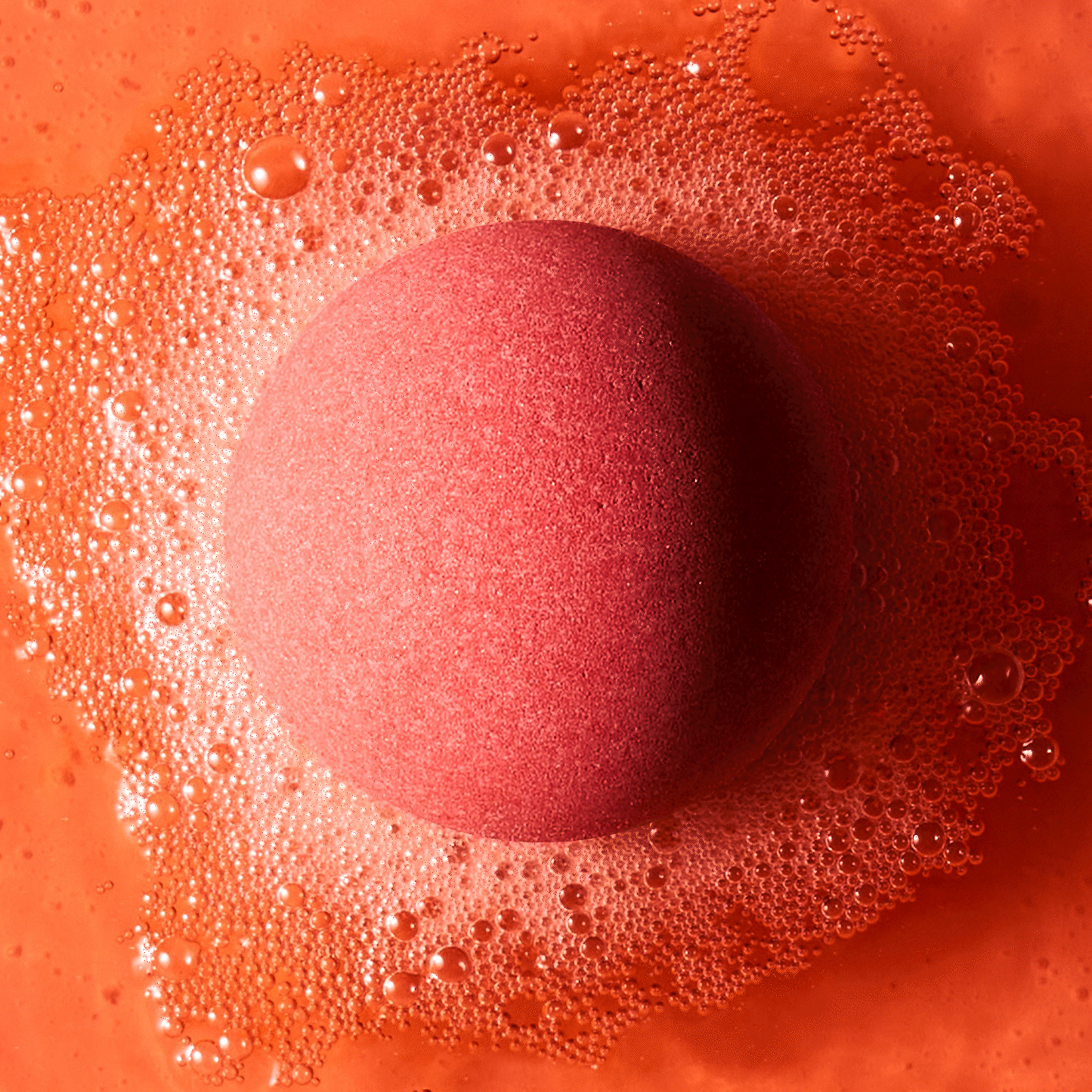 red bath bomb fizzing in water