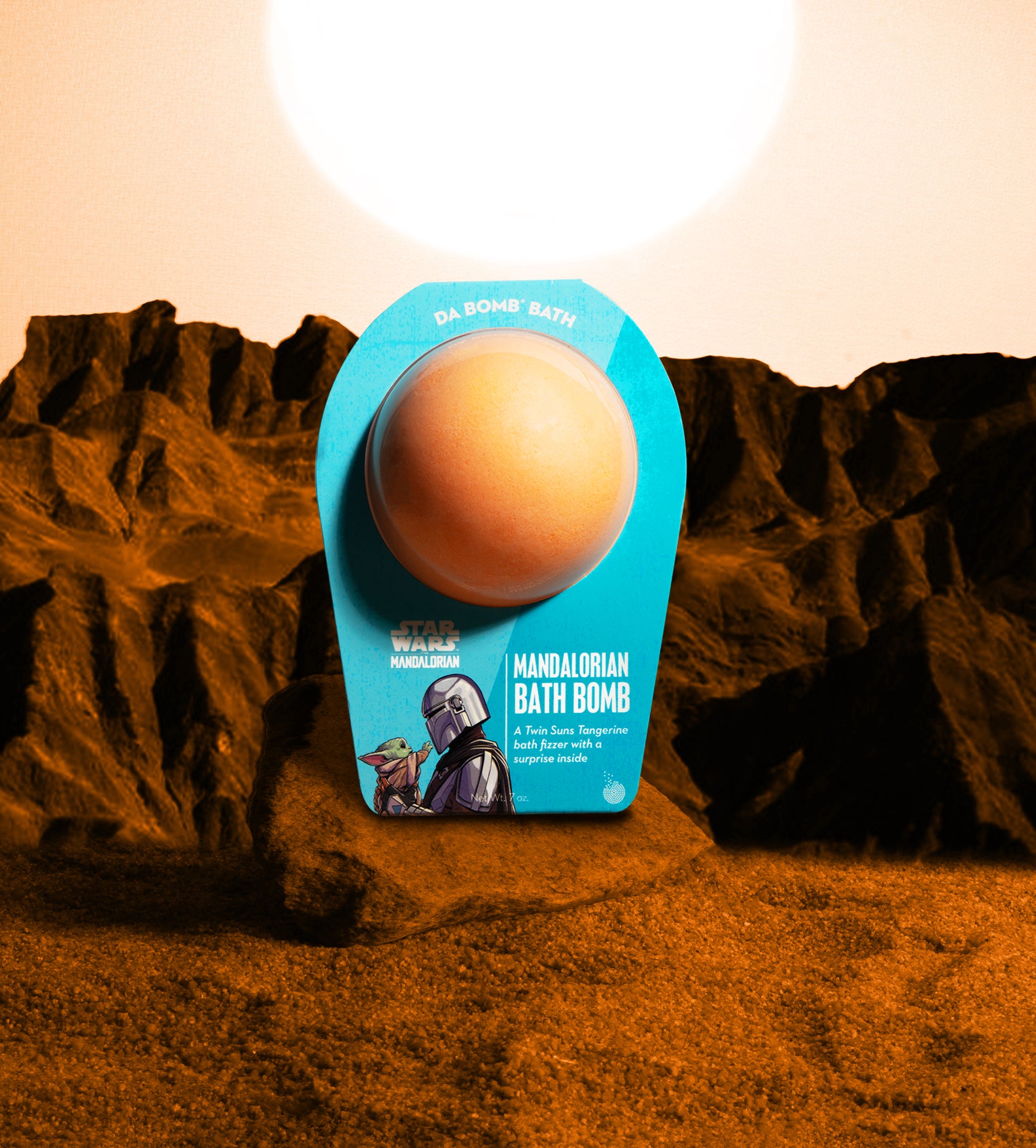 an orange bath bomb in blue packing on a rock in the desert
